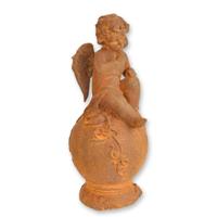 A RUSTY CAST IRON FIGURINE OF A PUTTO SITTING ON BALL