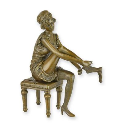 A BRONZE SCULPTURE OF A WOMAN PUTTING ON HER SOCKS