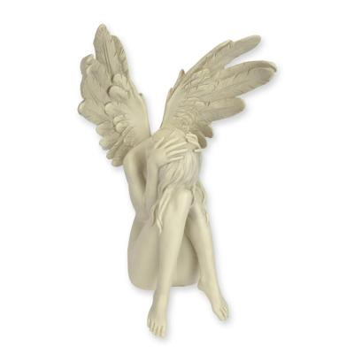 A RESIN FIGURINE OF A RECLINING ANGEL