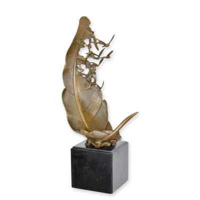 A BRONZE SCULPTURE OF A PIGEOONS FLYING OUT A LEAF