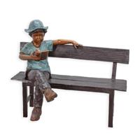 A BRONZE SCULPTURE OF A BOY SITTING ON A BENCH