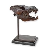 A BRONZE SCULPTURE OF A DIRE WOLF SKULL ON A MARBLE BASE