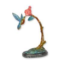 A BRONZE SCULPTURE OF A HUMMING BIRD FEEDING ON A FLOWER