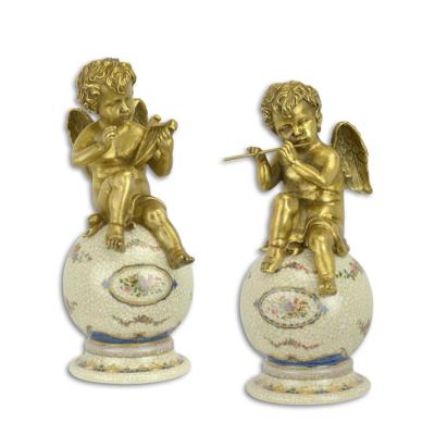 A PAIR OF BRONZE PUTTI ON PORCELAIN BALL