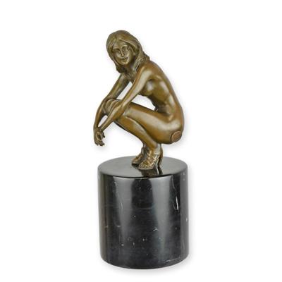 A BRONZE SCULPTURE OF A COWERING NUDE