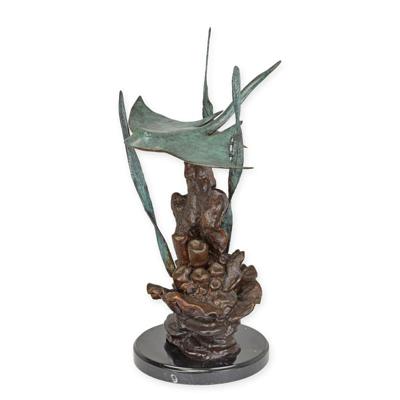 A BRONZE SCULPTURE OF A STINGRAY SWIMMING IN CORAL